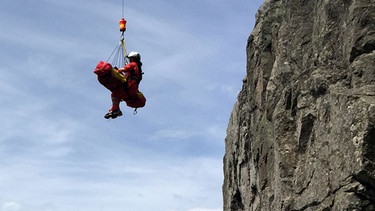 Ein Bergretter seilt einen verunglückten Wanderer ab. | Bild: picture-alliance/dpa